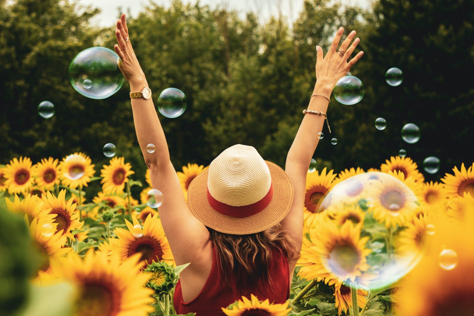 Woman dancing in a field of sunflowers and bubbles.