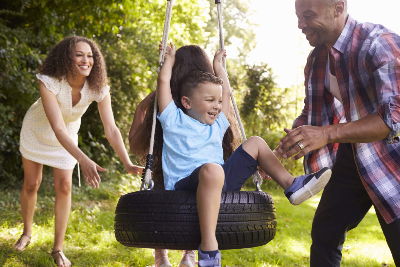 Happy family playing outside on a tire swing