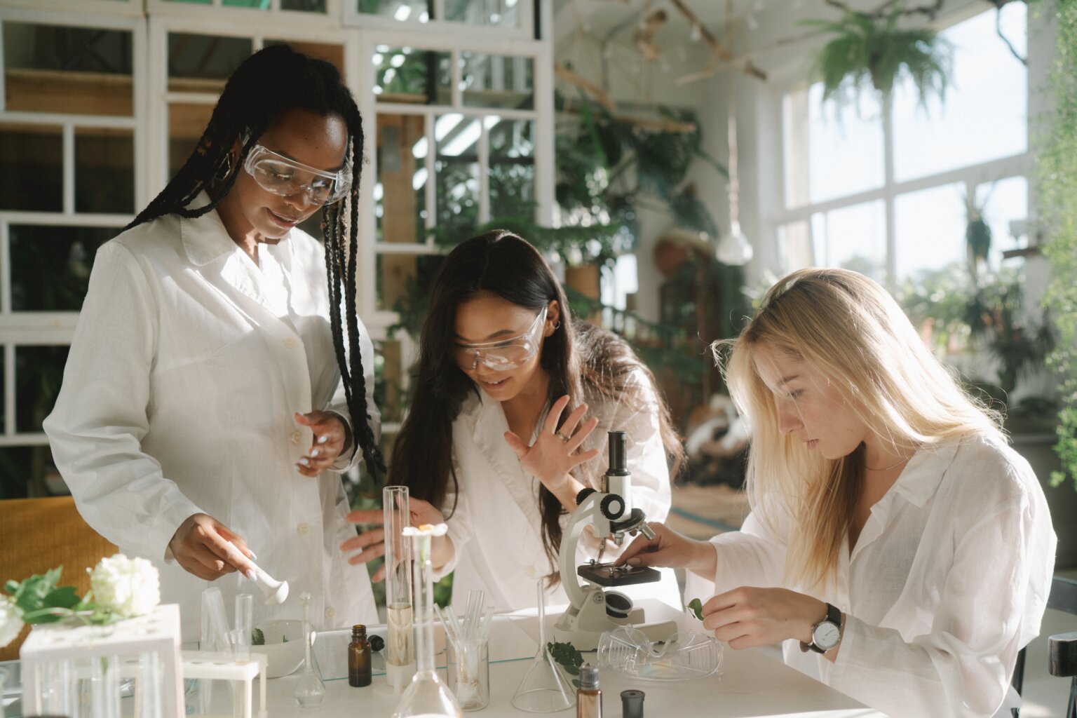 Three girls examining plants under a microscope.