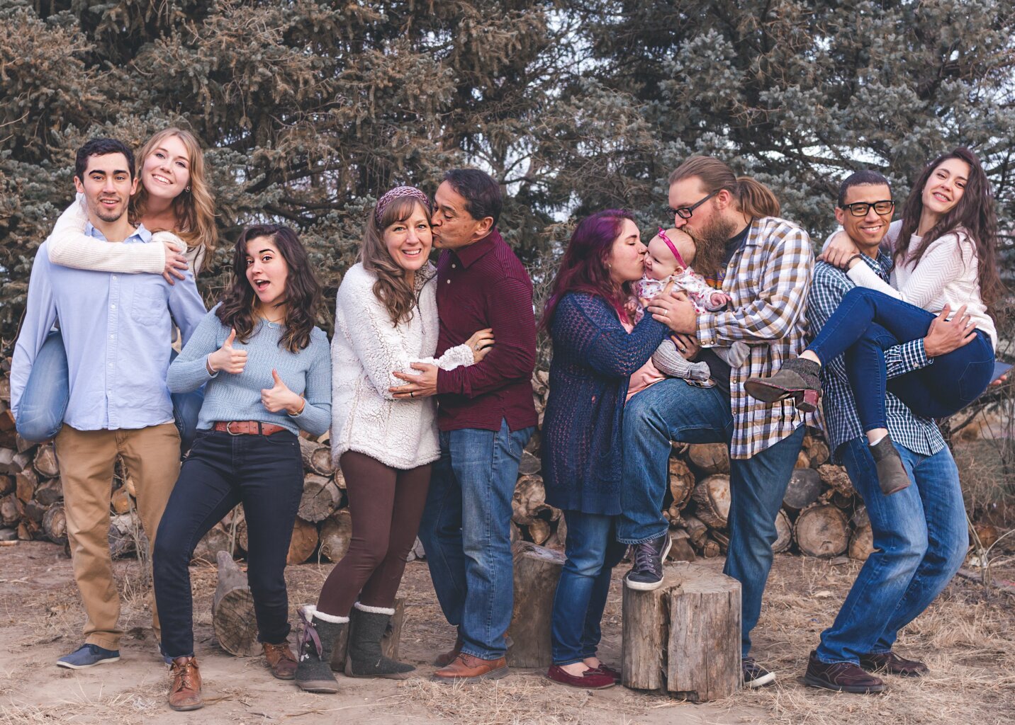 A family of ten, including four man and woman couples, a single woman, and a baby, taking a photo together.