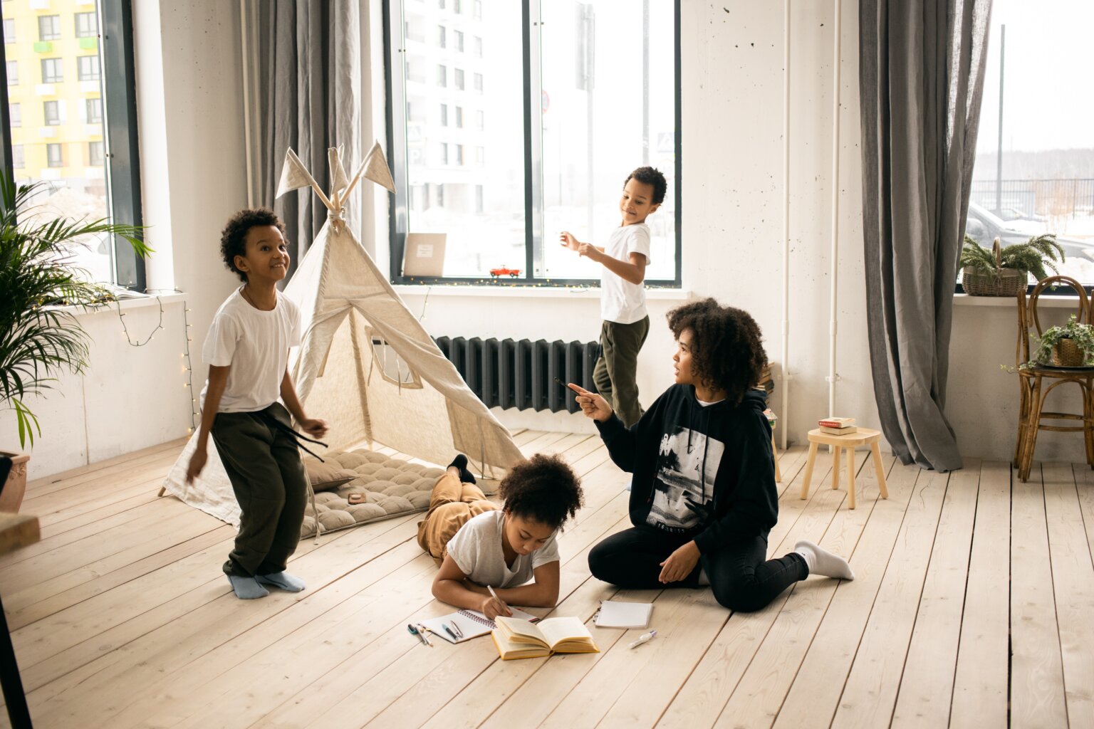 A group of siblings playing around a tent in their living room.
