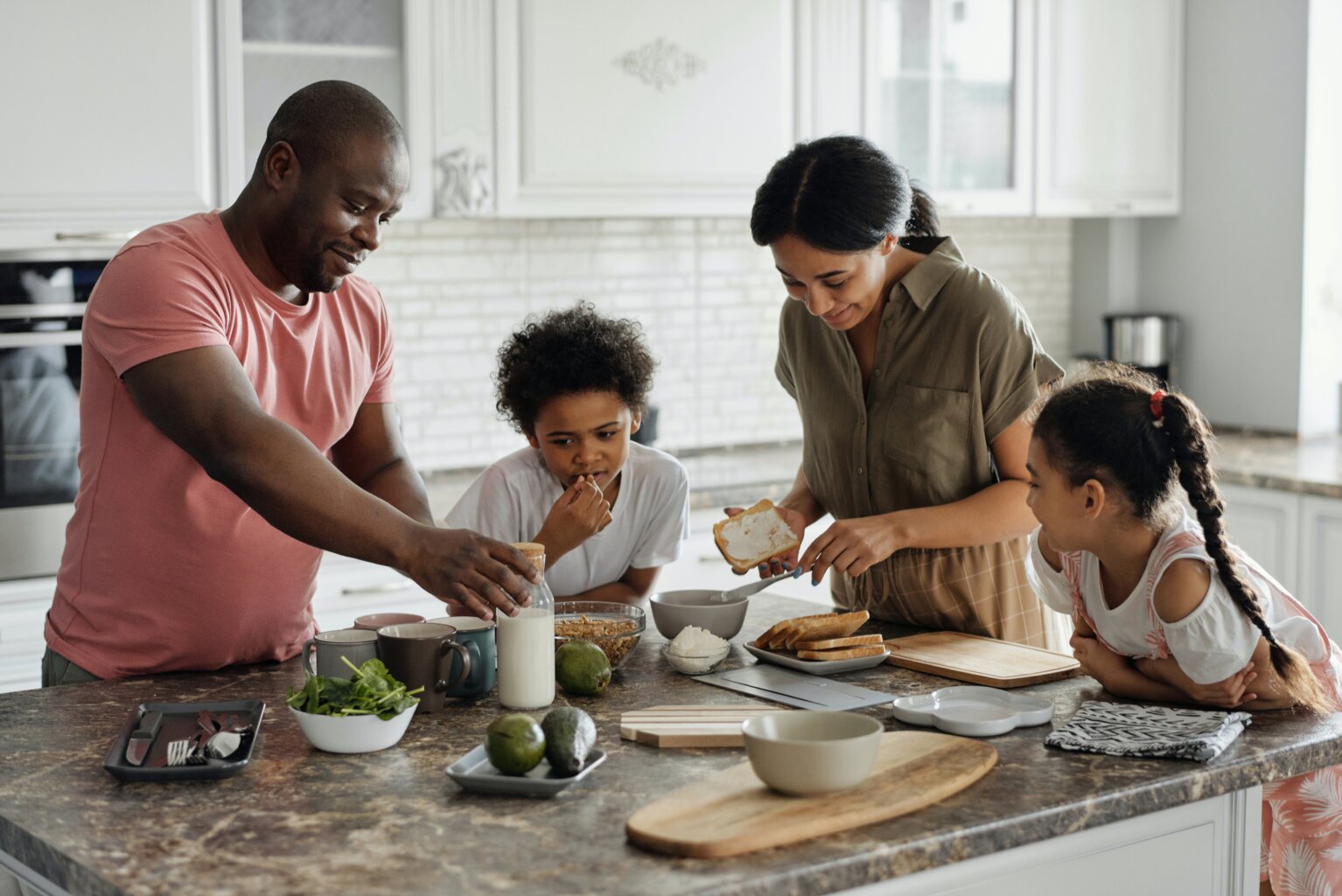 A mom, dad, and their son and daughter cooking together in the kitchen.