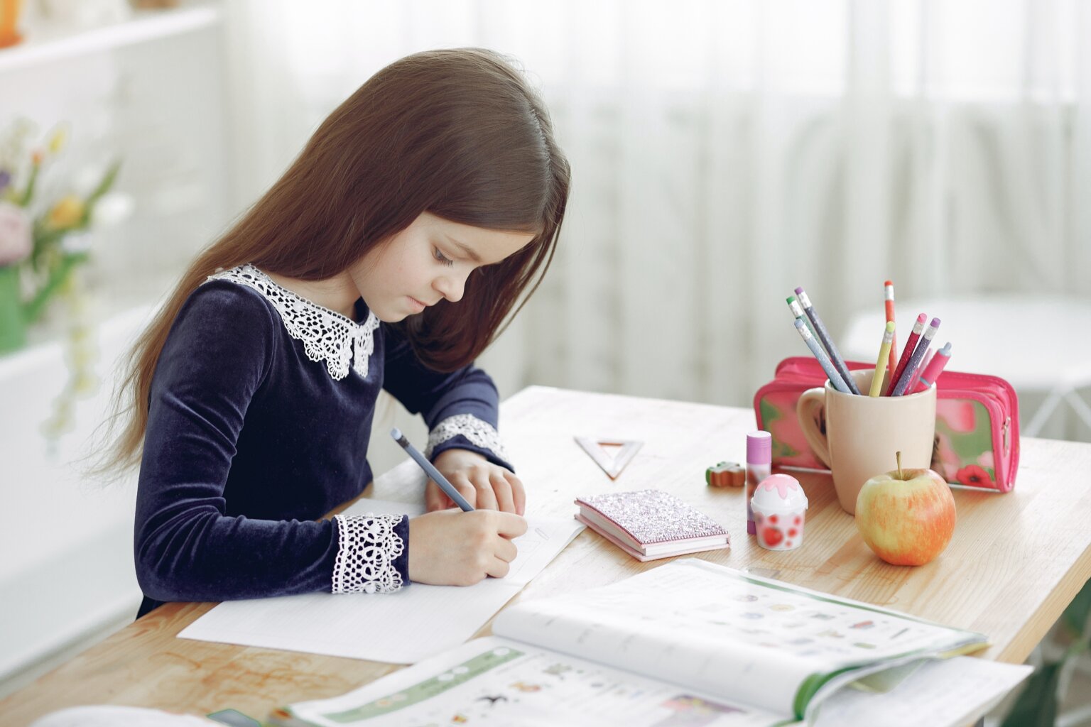 A girl working on homework at her desk in her home study space.