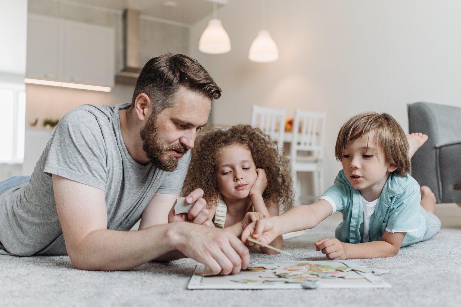 A father putting a puzzle together with his son and daughter to make learning fun.