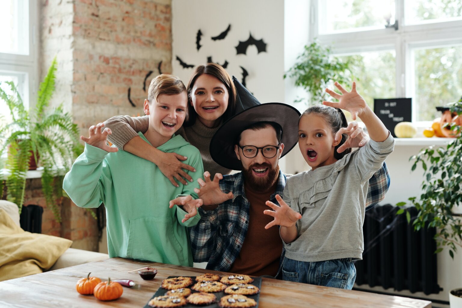 A dad, mom, son, and daughter making cookies as a Halloween activity.