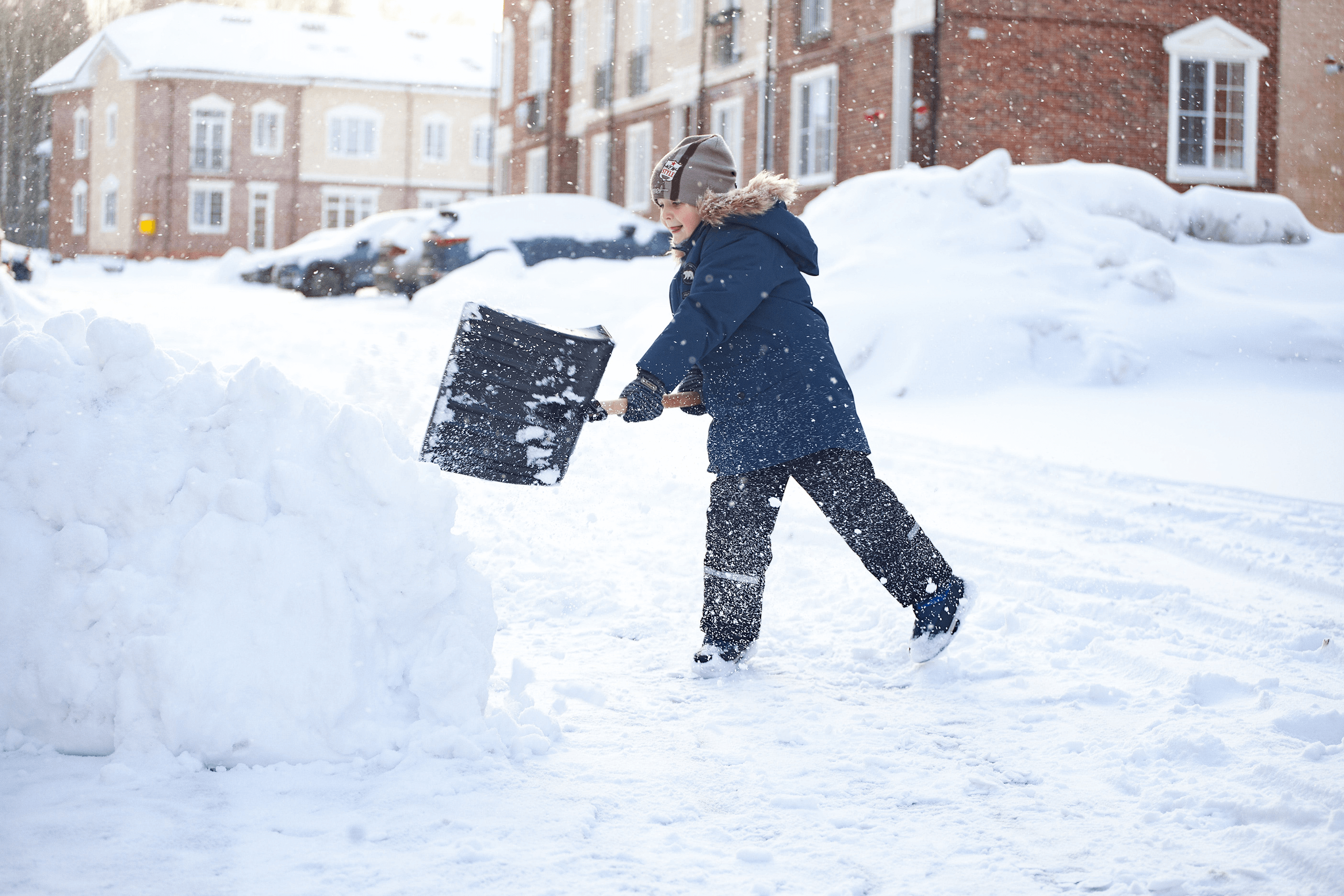A kid shoveling snow in a neighbor’s driveway to give back during the holiday season.