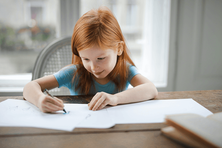 A redheaded girl doodling on paper as a form of letter writing.