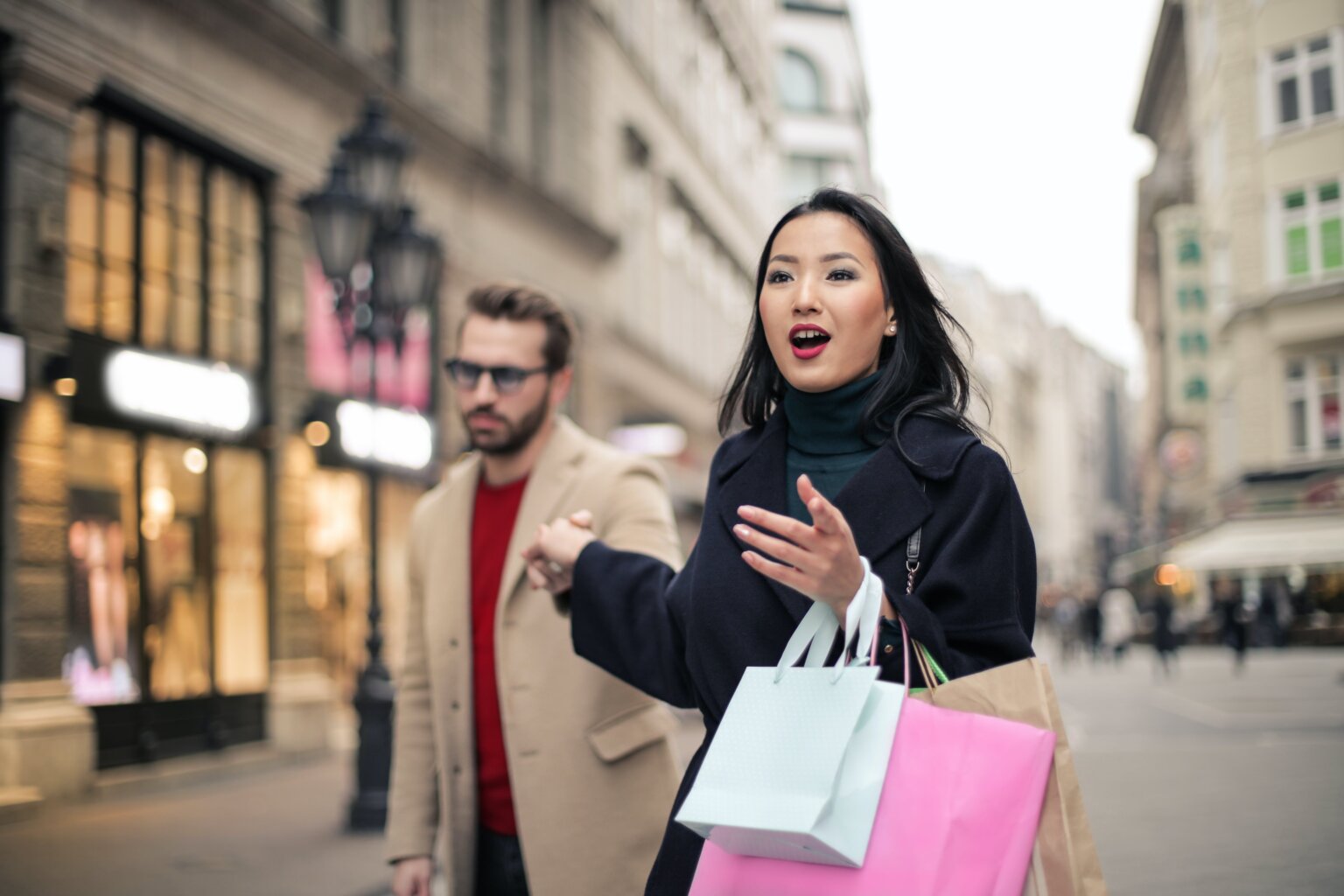 Woman holding shopping bags and a man’s hand as they shop together on Black Friday.